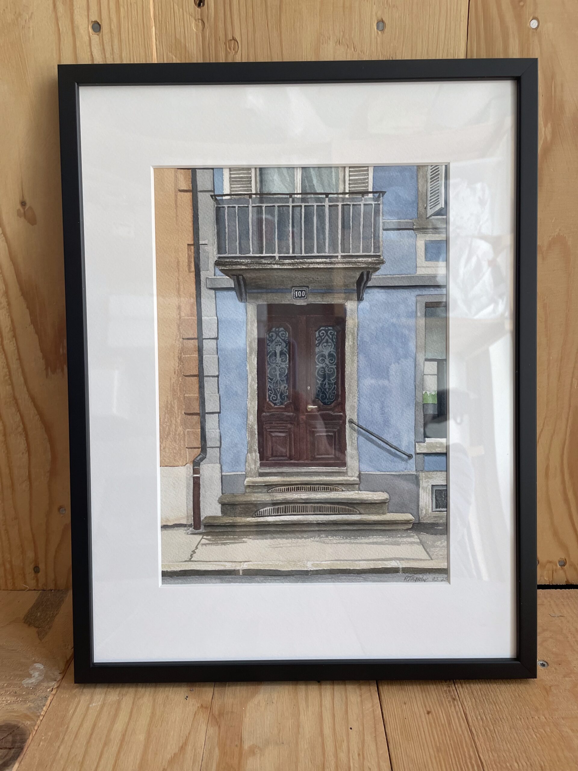 Peinture à l'aquarelle d'une porte en bois à La Chaux-de-Fonds, entre des murs bleues. Encadré en noir.