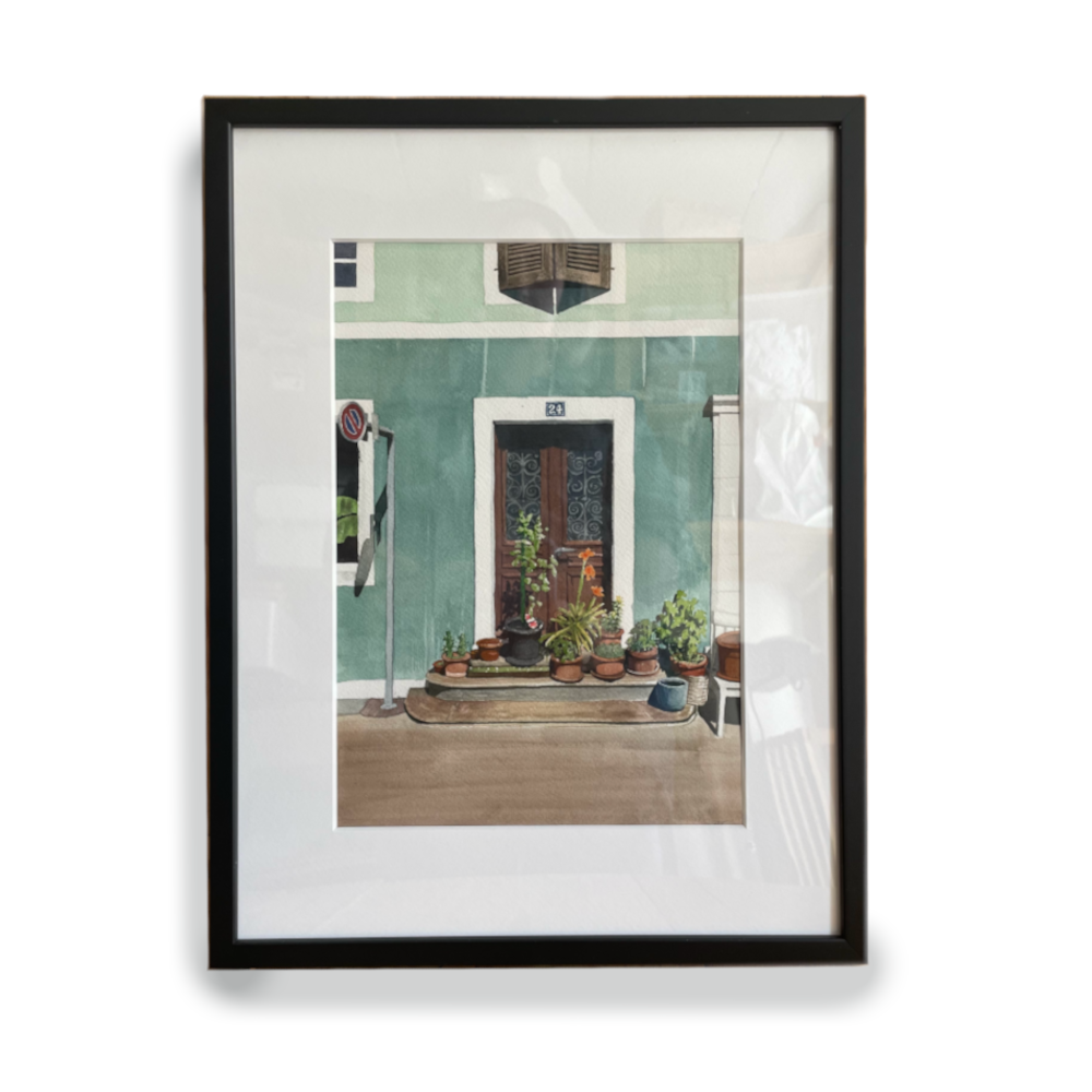 Peinture à l'aquarelle d'une porte en bois à La Chaux-de-Fonds, entre des murs vertes, avec des plants dans l'avant plan. Encadré en noir.